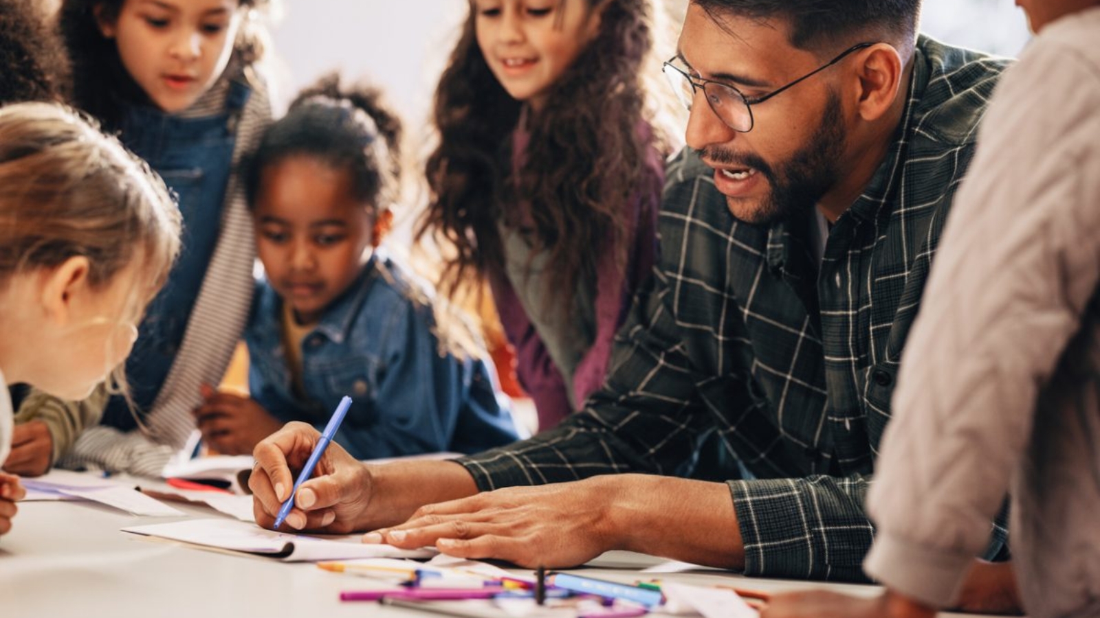 Male-teacher-sitting-with-elementary-students-and-drawing-1200x801
